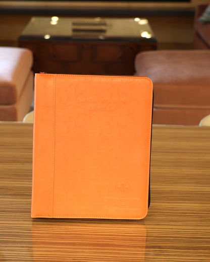 The orange CLEAR Kit Essentials binder standing on a table