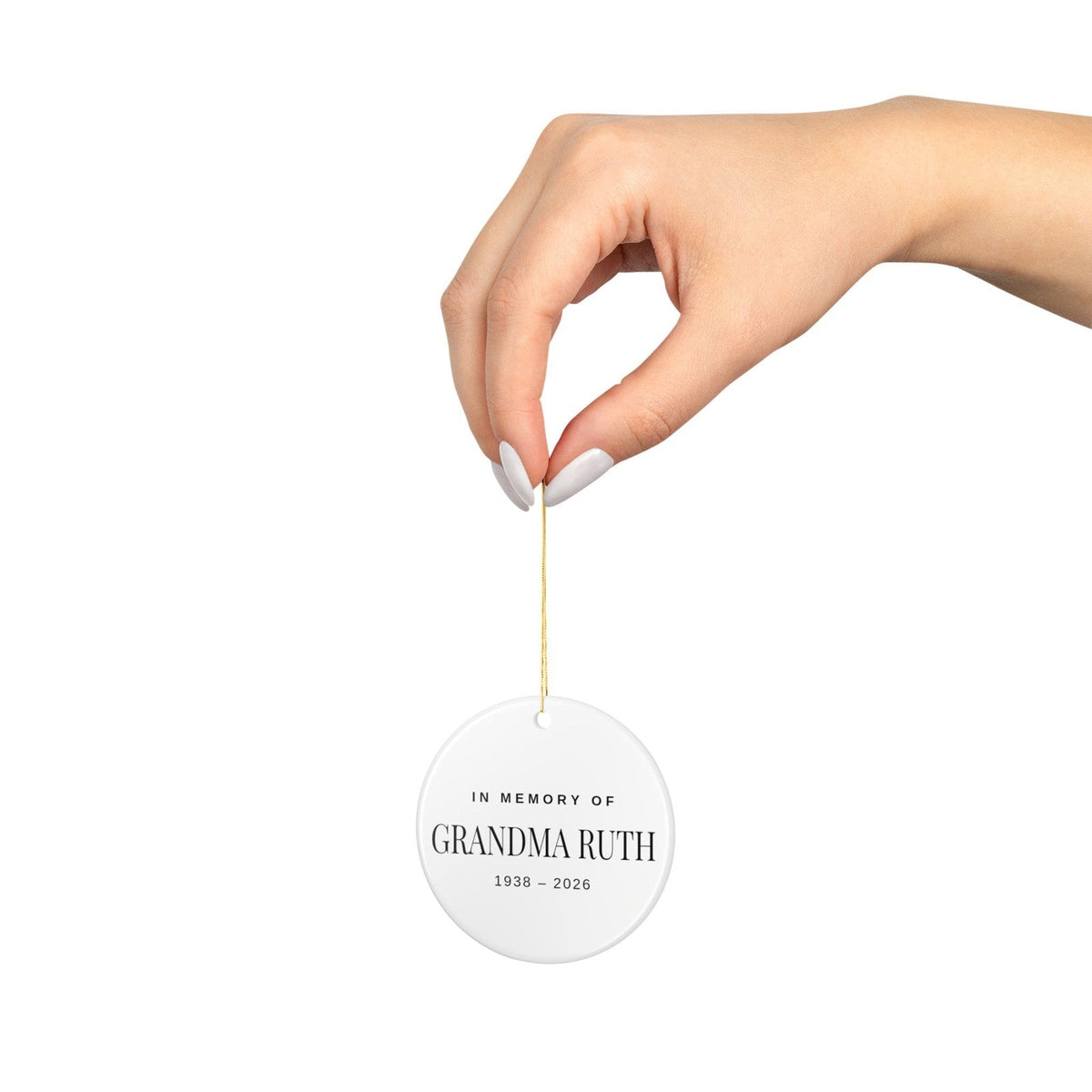 The round ornament hanging from its gold string, shown at actual size in a hand