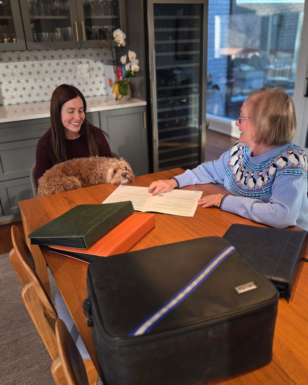Two people at a kitchen table with the CLEAR Kit binders and case